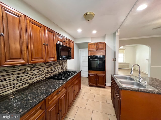 kitchen featuring dark stone counters, black appliances, decorative backsplash, sink, and light tile patterned floors