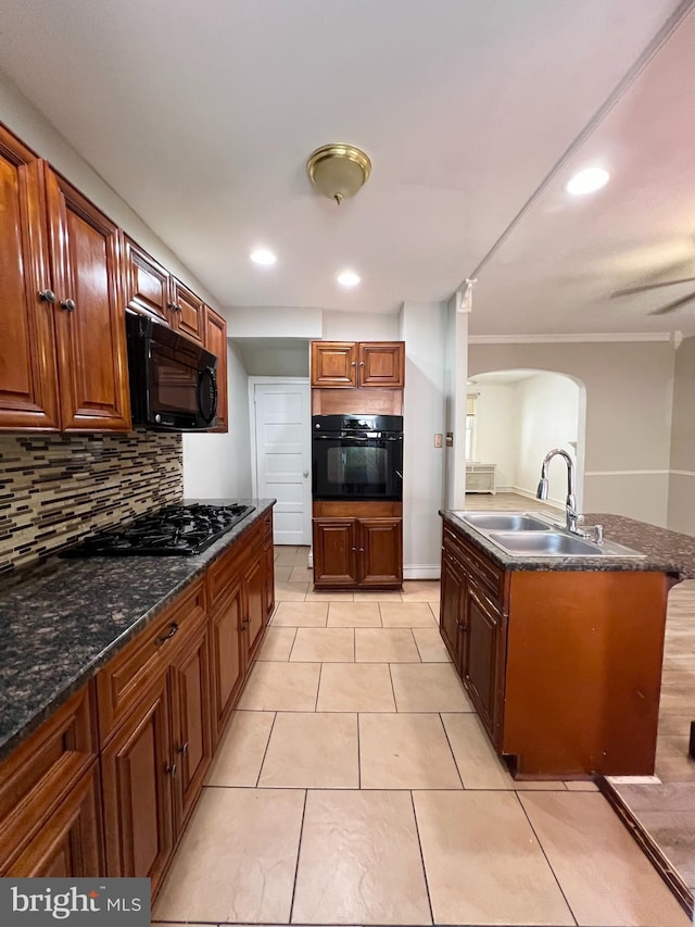 kitchen with light tile patterned flooring, tasteful backsplash, dark stone counters, black appliances, and sink