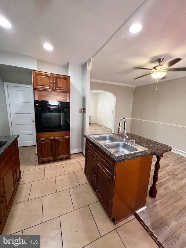 kitchen featuring light tile patterned flooring, ceiling fan, crown molding, sink, and black oven