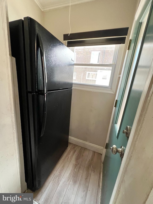 interior space featuring light hardwood / wood-style flooring, black fridge, and ornamental molding