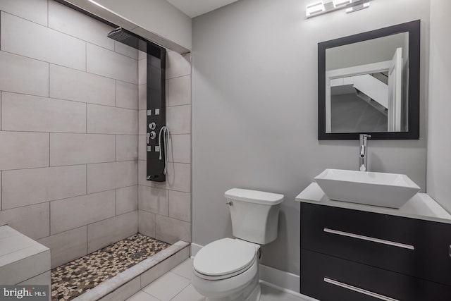 bathroom with tile patterned floors, vanity, a tile shower, and toilet