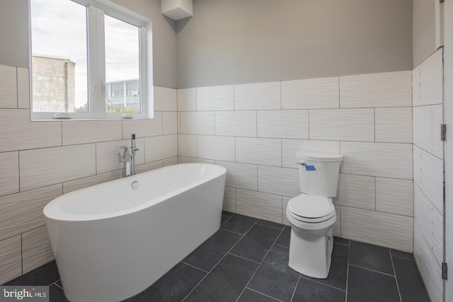 bathroom featuring toilet, tile patterned flooring, and tile walls