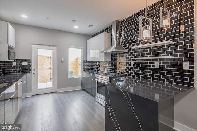 kitchen with high end stainless steel range oven, wood-type flooring, white cabinets, and wall chimney range hood