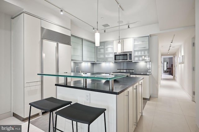 kitchen featuring light tile patterned floors, tasteful backsplash, a kitchen breakfast bar, pendant lighting, and a kitchen island