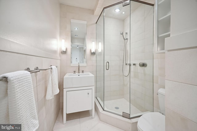 bathroom featuring vanity, tile walls, tile patterned flooring, toilet, and a shower with shower door