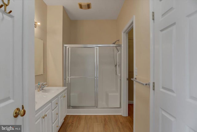 bathroom with wood-type flooring, a shower with shower door, and vanity