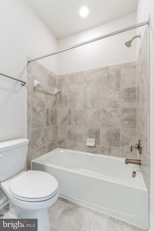 bathroom featuring tile patterned flooring, tiled shower / bath combo, and toilet