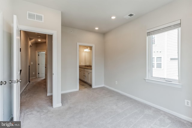 unfurnished bedroom with light colored carpet and connected bathroom