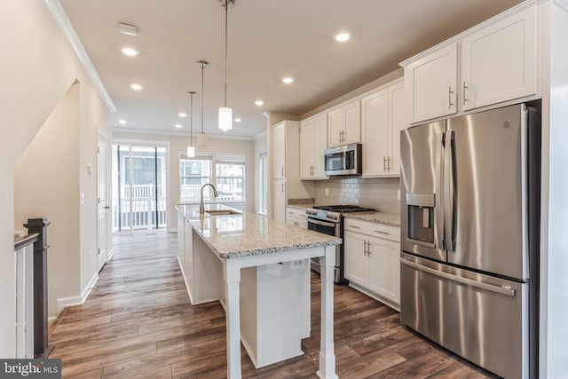 kitchen featuring pendant lighting, a kitchen island with sink, white cabinets, light stone countertops, and stainless steel appliances