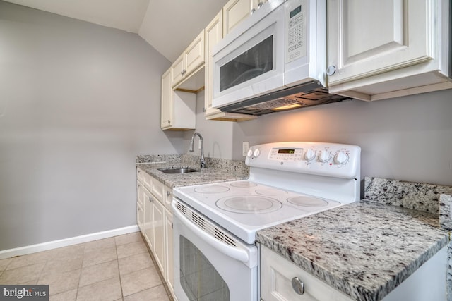 kitchen featuring light stone countertops, white appliances, vaulted ceiling, sink, and light tile patterned flooring