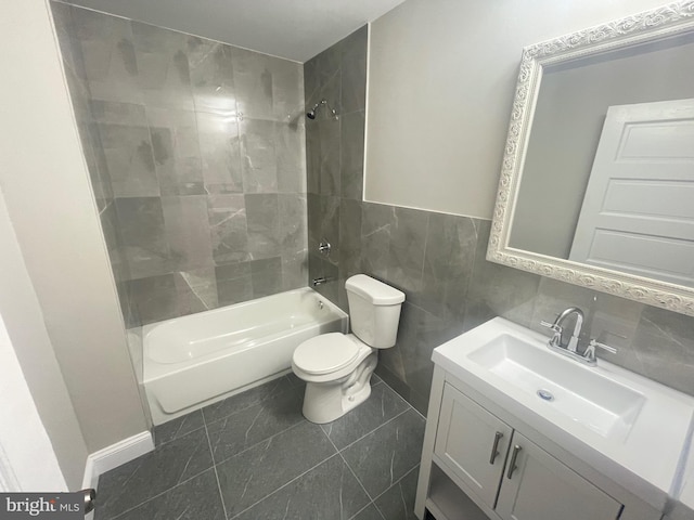 full bathroom featuring vanity, tiled shower / bath combo, tile walls, and toilet