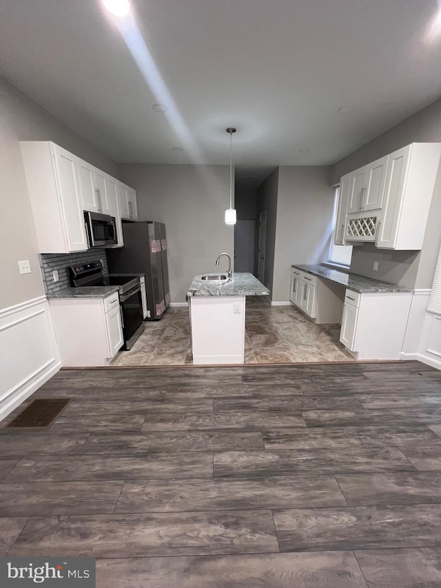 kitchen with stainless steel appliances, white cabinetry, a kitchen island with sink, and sink