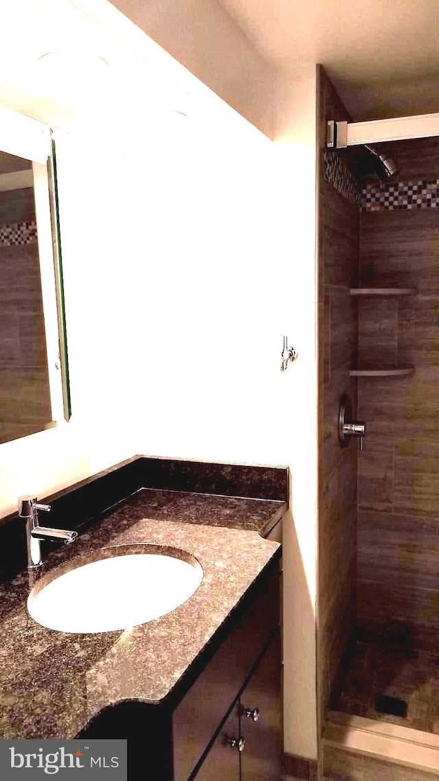 bathroom with tiled shower and vanity