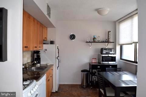 kitchen featuring plenty of natural light, white appliances, sink, and tasteful backsplash