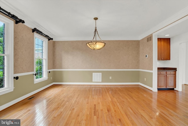 empty room with ornamental molding and light wood-type flooring