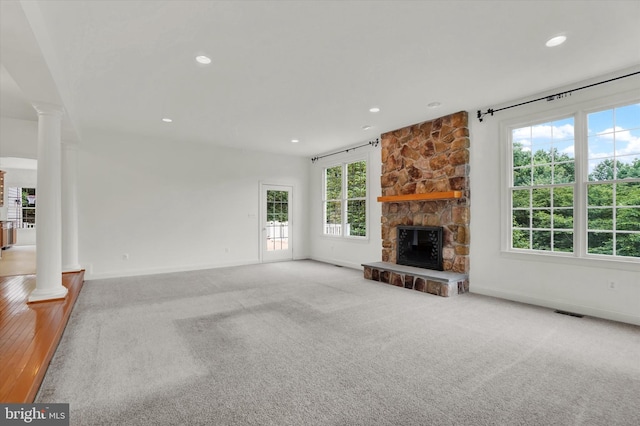 unfurnished living room with a fireplace, decorative columns, and carpet