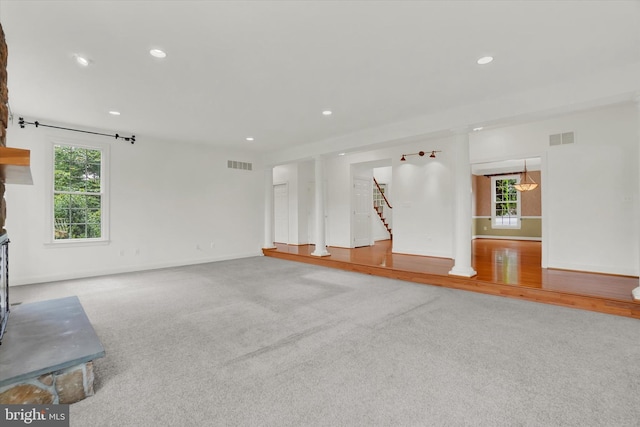 unfurnished living room with carpet and plenty of natural light