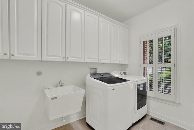 washroom with independent washer and dryer, cabinets, light tile patterned floors, and sink