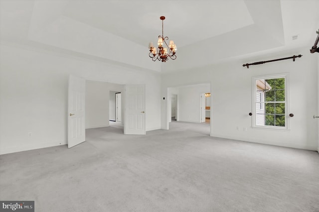 unfurnished living room featuring light colored carpet, an inviting chandelier, and a raised ceiling