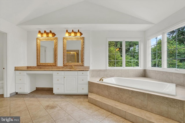 bathroom with vaulted ceiling, tile patterned flooring, toilet, vanity, and a relaxing tiled tub