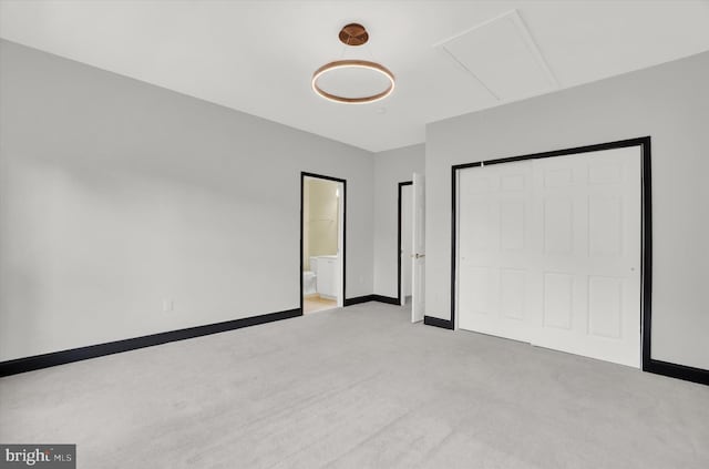 unfurnished bedroom with light colored carpet and connected bathroom