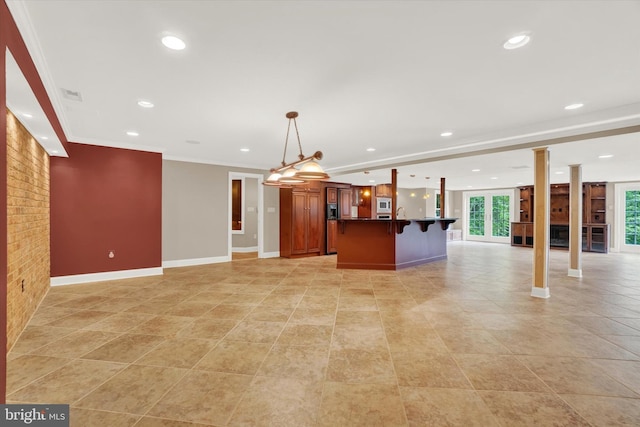 kitchen featuring hanging light fixtures, a center island, ornamental molding, a breakfast bar, and stainless steel microwave