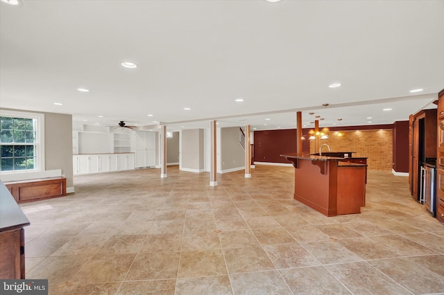 kitchen featuring sink, a kitchen breakfast bar, ceiling fan, hanging light fixtures, and brick wall