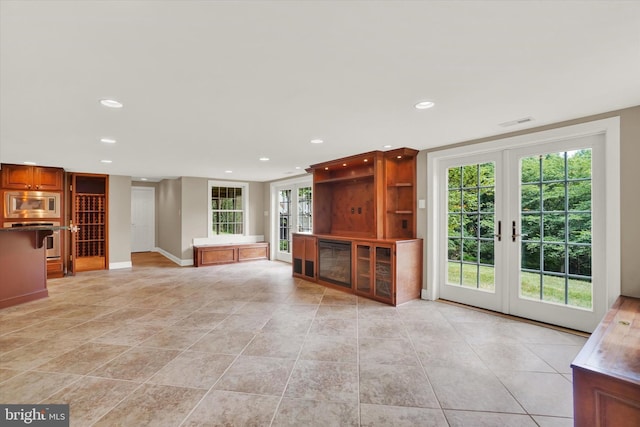 unfurnished living room featuring a healthy amount of sunlight and french doors