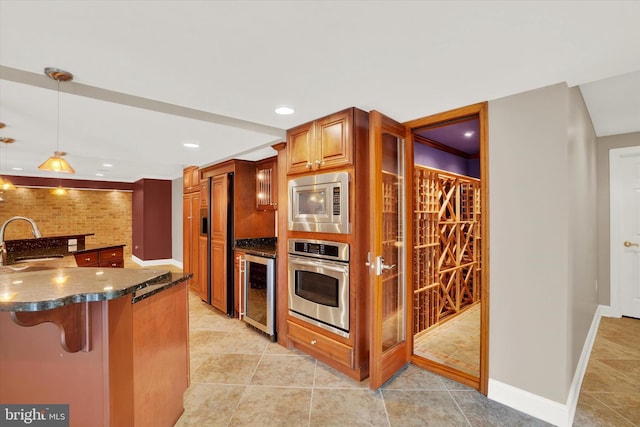 kitchen with built in appliances, hanging light fixtures, beverage cooler, a kitchen breakfast bar, and sink