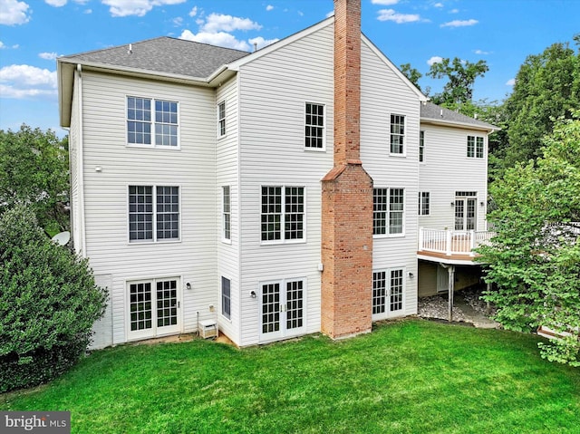 rear view of house featuring french doors, a wooden deck, and a yard