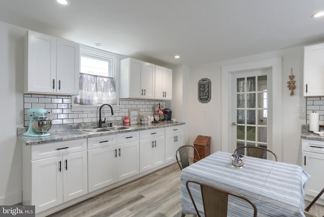 kitchen featuring decorative backsplash, white cabinetry, and sink