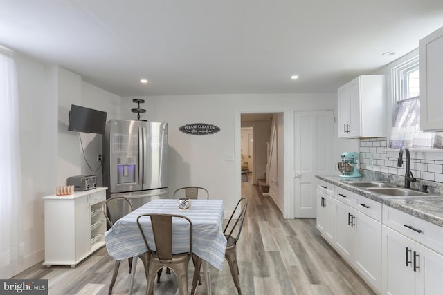 kitchen featuring stainless steel fridge, sink, white cabinets, and light wood-type flooring