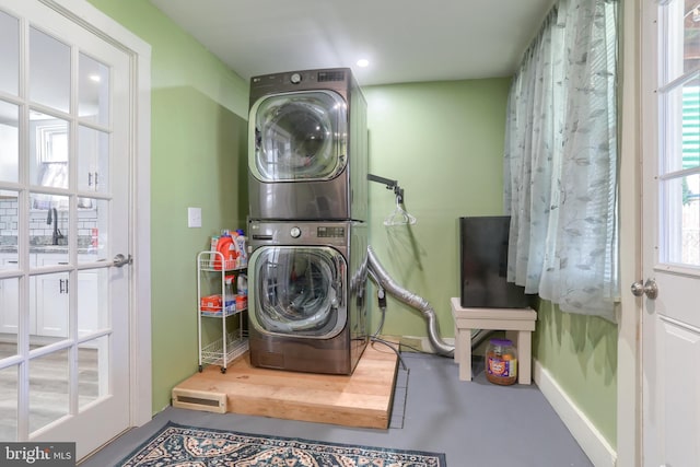 washroom with stacked washing maching and dryer and a wealth of natural light