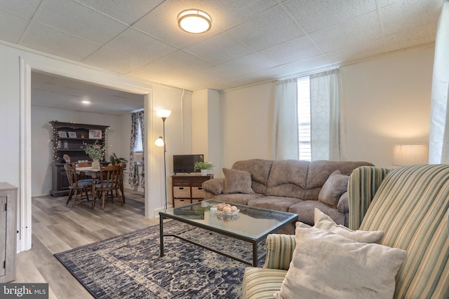 living room featuring light wood-type flooring and a paneled ceiling