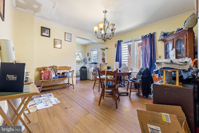 dining room with hardwood / wood-style flooring, ornamental molding, and an inviting chandelier