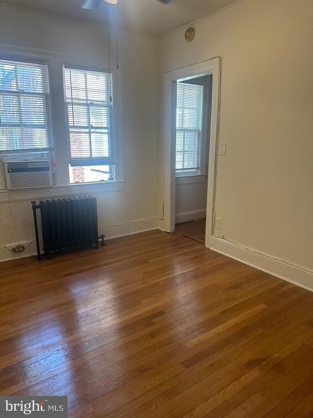 unfurnished room with wood-type flooring, radiator, cooling unit, and ceiling fan