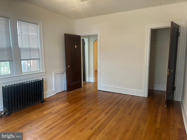 unfurnished bedroom with radiator and hardwood / wood-style floors