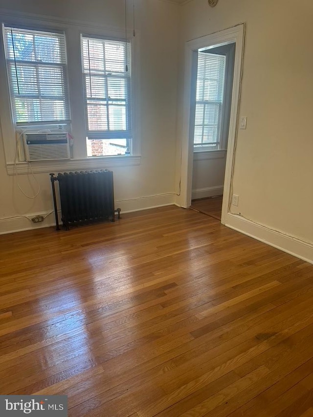 empty room featuring a healthy amount of sunlight, hardwood / wood-style floors, and cooling unit