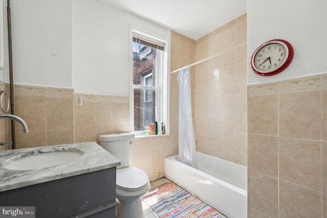 full bathroom featuring shower / bath combination with curtain, toilet, vanity, tile walls, and tile patterned floors