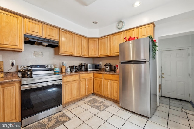 kitchen featuring appliances with stainless steel finishes, light tile patterned flooring, and dark stone counters