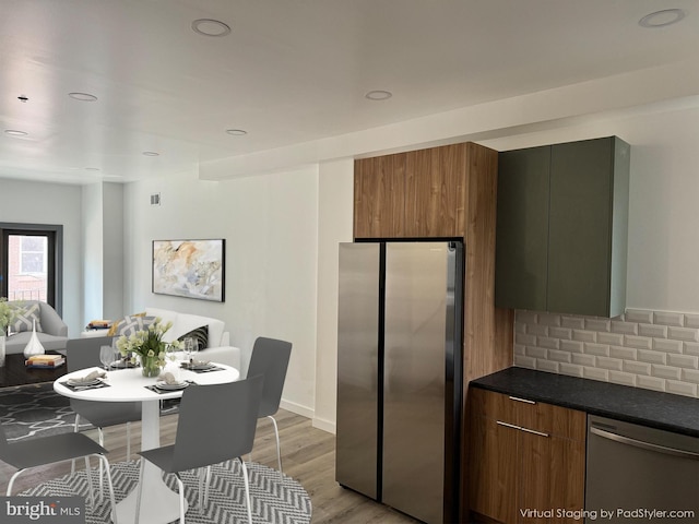 kitchen with tasteful backsplash, stainless steel appliances, and light hardwood / wood-style floors