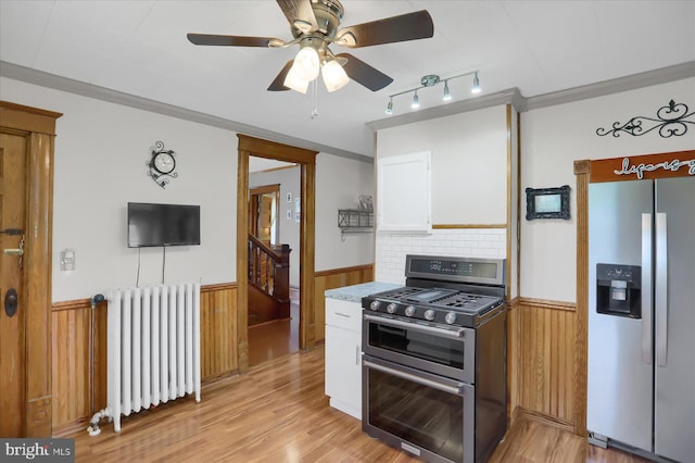 kitchen with white cabinetry, ceiling fan, radiator, appliances with stainless steel finishes, and light hardwood / wood-style flooring