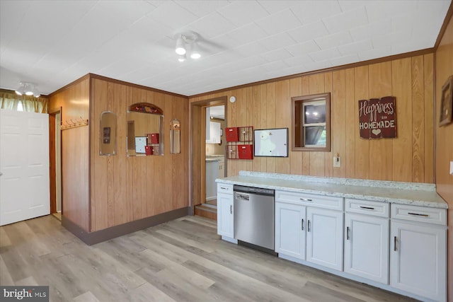 kitchen with stainless steel dishwasher, white cabinetry, light stone countertops, wood walls, and light hardwood / wood-style flooring