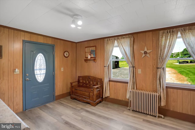 entrance foyer with plenty of natural light, wood walls, light wood-type flooring, and radiator heating unit