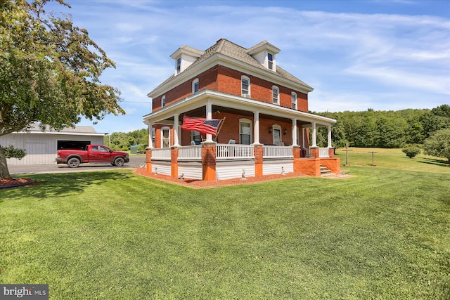 view of front facade featuring covered porch, an outbuilding, and a front yard