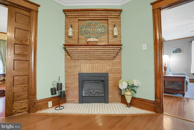 living room featuring hardwood / wood-style flooring, a brick fireplace, brick wall, and ornamental molding