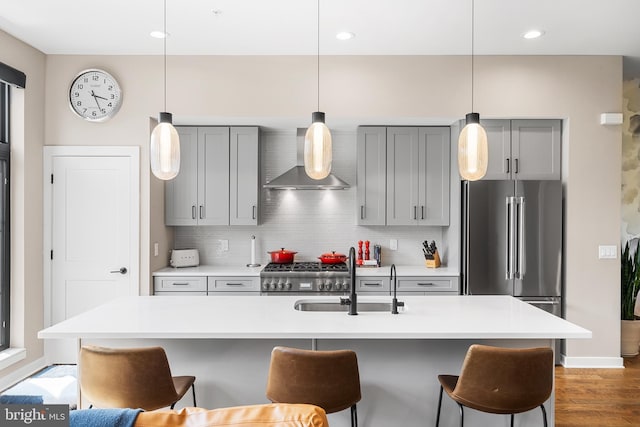 kitchen featuring pendant lighting, wall chimney range hood, sink, and high quality fridge