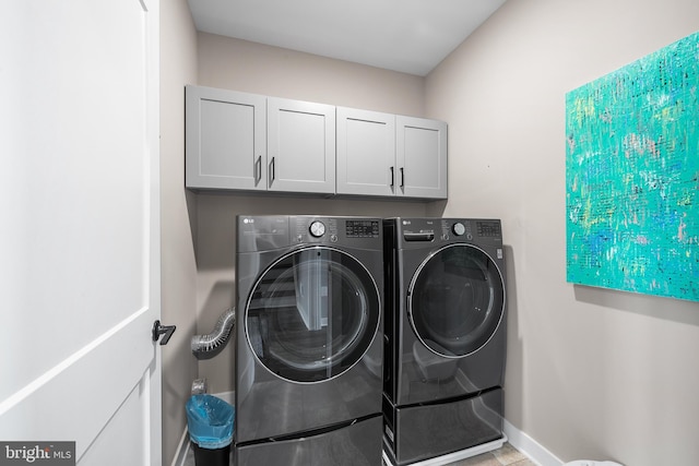 washroom featuring washer and dryer, cabinets, and light tile patterned floors