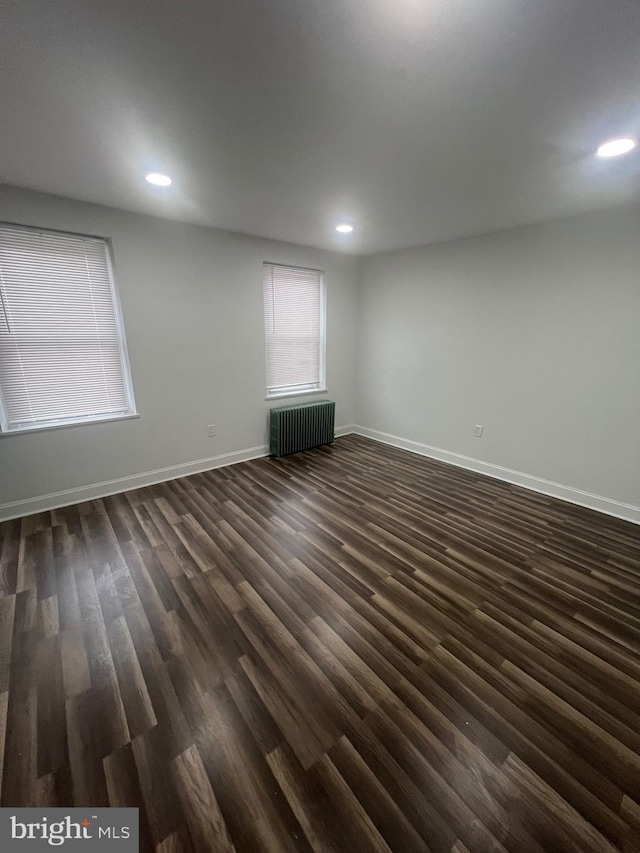 unfurnished room featuring dark hardwood / wood-style flooring and radiator