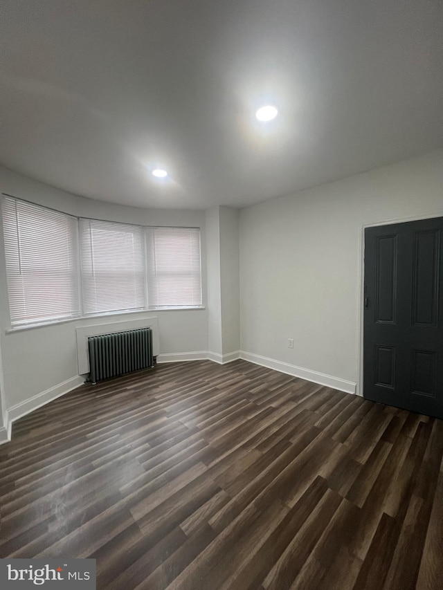 empty room with dark wood-type flooring and radiator